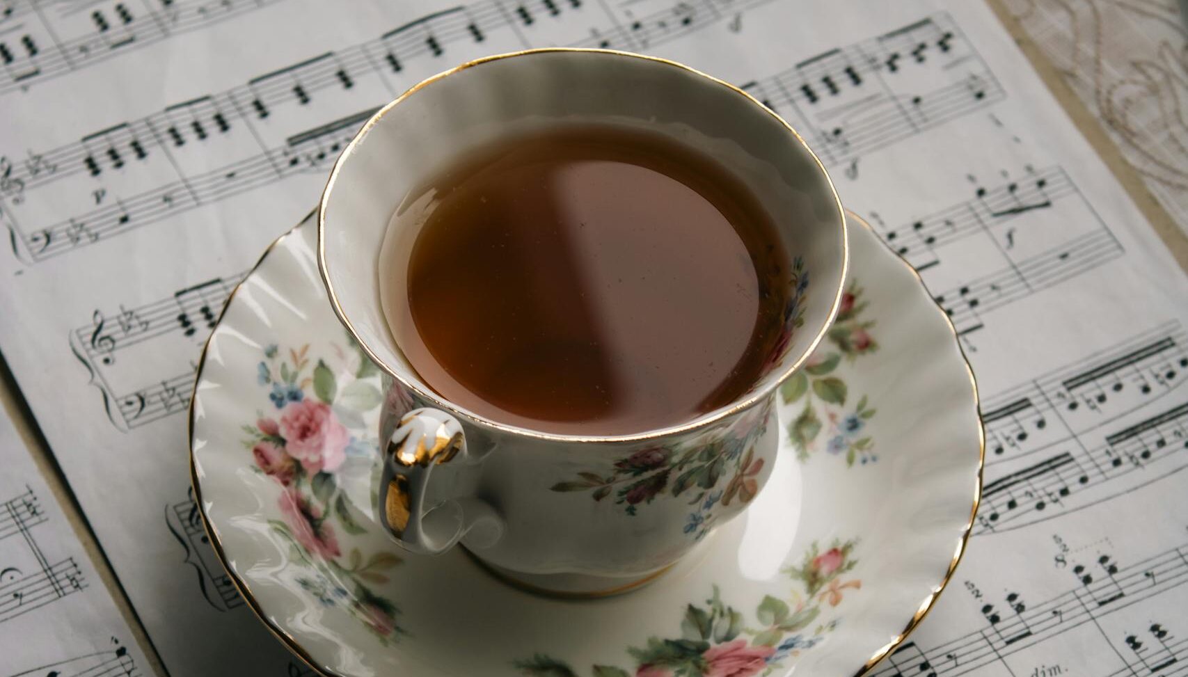 A vintage floral teacup atop music sheets, blending elegance and art.